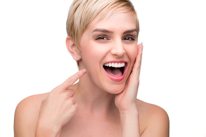 Lächelnde Person, die ihre weißen Zähne mit dem rechten Zeigefinger präsentiert