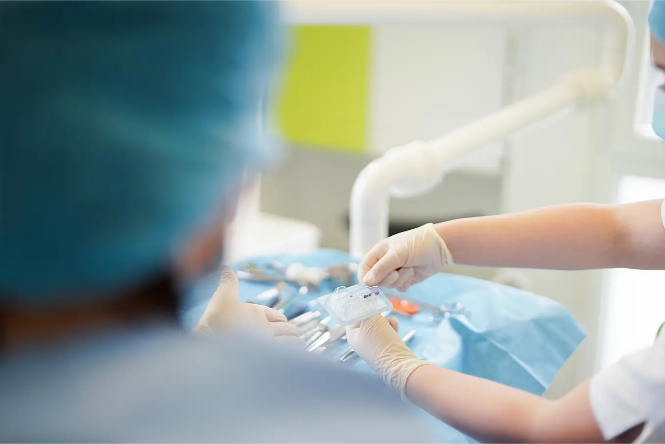 Zahnärztinnen in einer modernen Praxis im Gespräch mit einem Patienten, während sie Behandlungsmöglichkeiten auf einem Tablet erklären.
